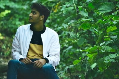 Portrait of young man sitting on tree