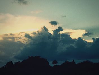 Silhouette of trees against cloudy sky