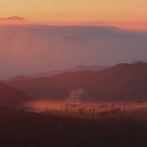 Scenic view of silhouette mountains against orange sky