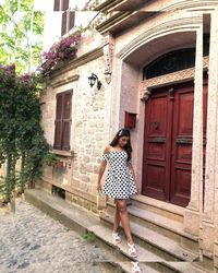 Full length portrait of woman standing outside building