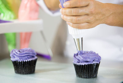 Close-up of chef icing cupcakes