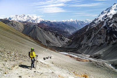 Man walking on snowcapped mountain against sky