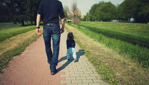 Low section of man walking with daughter on footpath