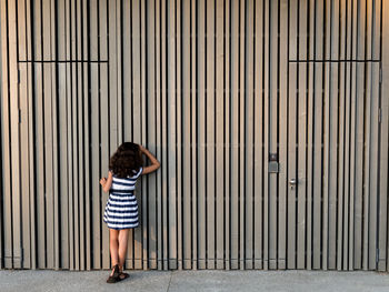Rear view of girl standing towards wall