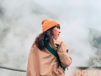 Low angle view of woman looking away against fog