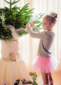 Side view of girl decorating christmas tree at home