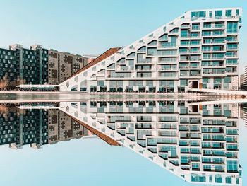 Reflection of buildings in lake against clear sky