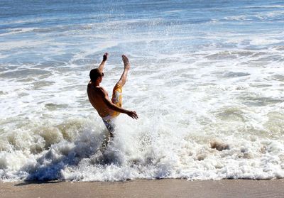 Shirtless man splashing water in sea