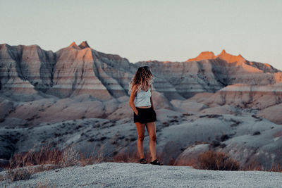 Rear view of woman standing on rock against sky