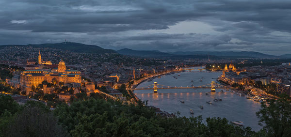 Szechenyi chain bridge over danube river in city at dusk