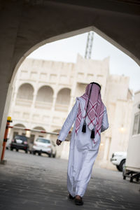 Rear view of woman standing on street against building