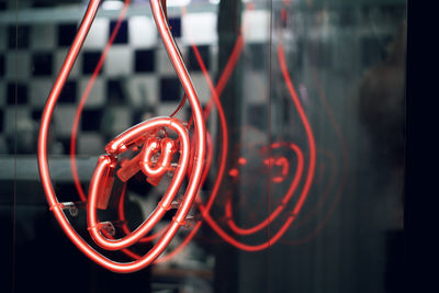 Close-up of red light hanging on metal at night