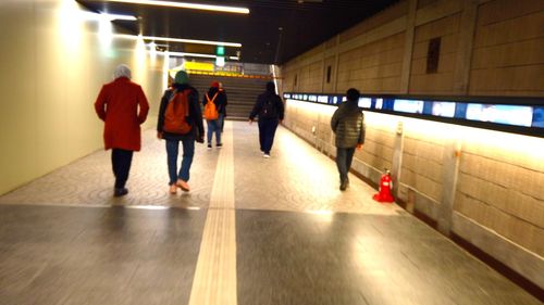 Rear view of people walking on subway station