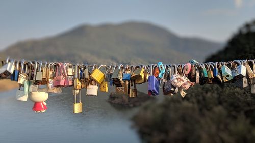 Multi colored padlocks hanging on mountain against sky