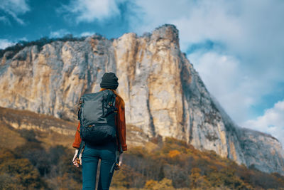 Rear view of man standing on rock against sky