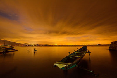 Boat moored in sea against sky during sunset