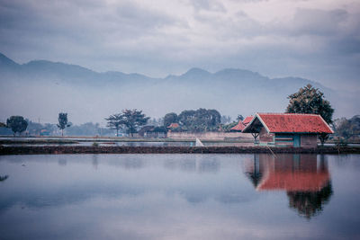 Scenic view of lake by buildings against sky