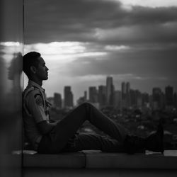 Side view of senior man sitting against cityscape