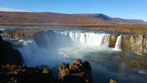 Scenic view of waterfall against sky