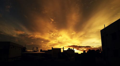 Silhouette of buildings against cloudy sky at sunset