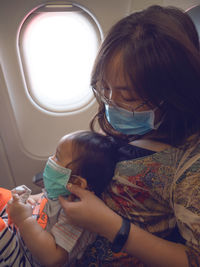 Mother and son wearing masks while sitting in airplane