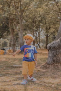 Full length of asian boy standing in forest