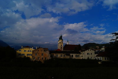 Buildings in town against cloudy sky