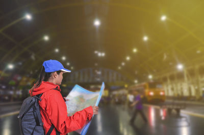 Young asian woman reading map while standing at railroad station platform. 