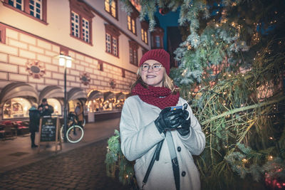 Smiling young woman standing in city at night