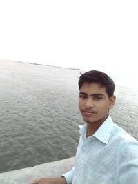 Portrait of young man in sea against clear sky