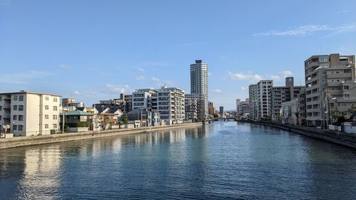 Buildings by river against sky