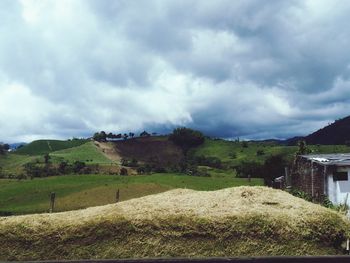 Scenic view of grassy field against cloudy sky