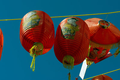 Low angle view of lanterns hanging against clear blue sky