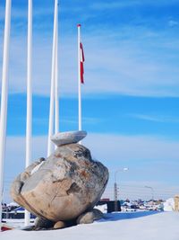 Flag on rock in sea against sky during winter