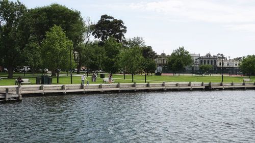 People by river in park against sky