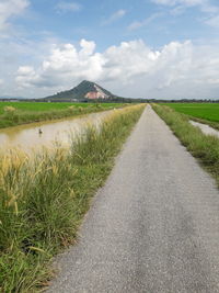 Road amidst field against sky