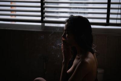 Woman smoking cigarette in bathroom