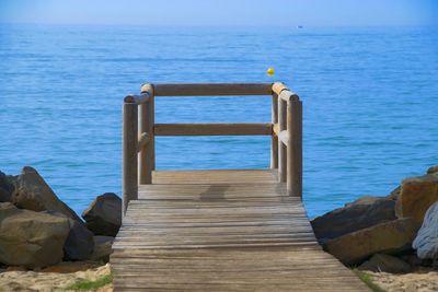Wooden posts on rocks by sea against sky