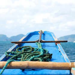 Close-up of rope tied on wooden post by sea against sky