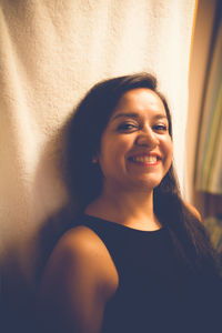 Portrait of a smiling young woman against wall