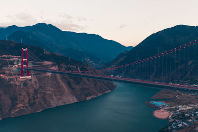 Bridge over river against mountains during sunset