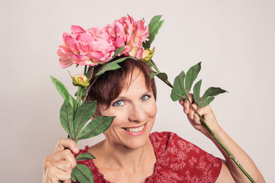 Portrait of woman with pink flowers against gray background