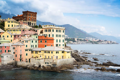 Buildings by sea against sky