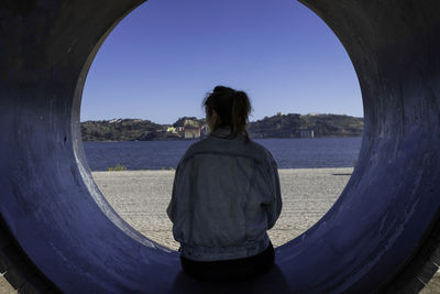 Rear view of man looking at sea against clear sky