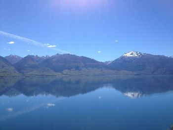 Scenic view of lake and mountains against blue sky