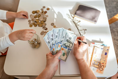 Cropped hands of man holding paper currency on table