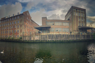 Bridge over river by buildings in city against sky