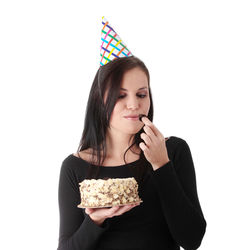 Portrait of young woman eating food against white background