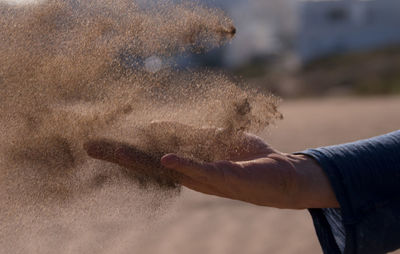 Midsection of man touching sand