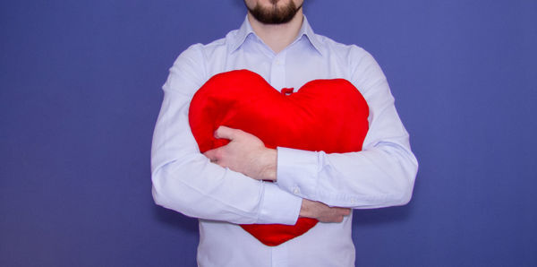 Midsection of man with heart shape against gray background